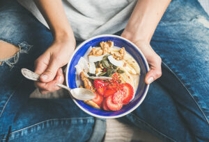 A woman eats a bowl of nutritious foods, which is a key part of a holistic approach to recovery.